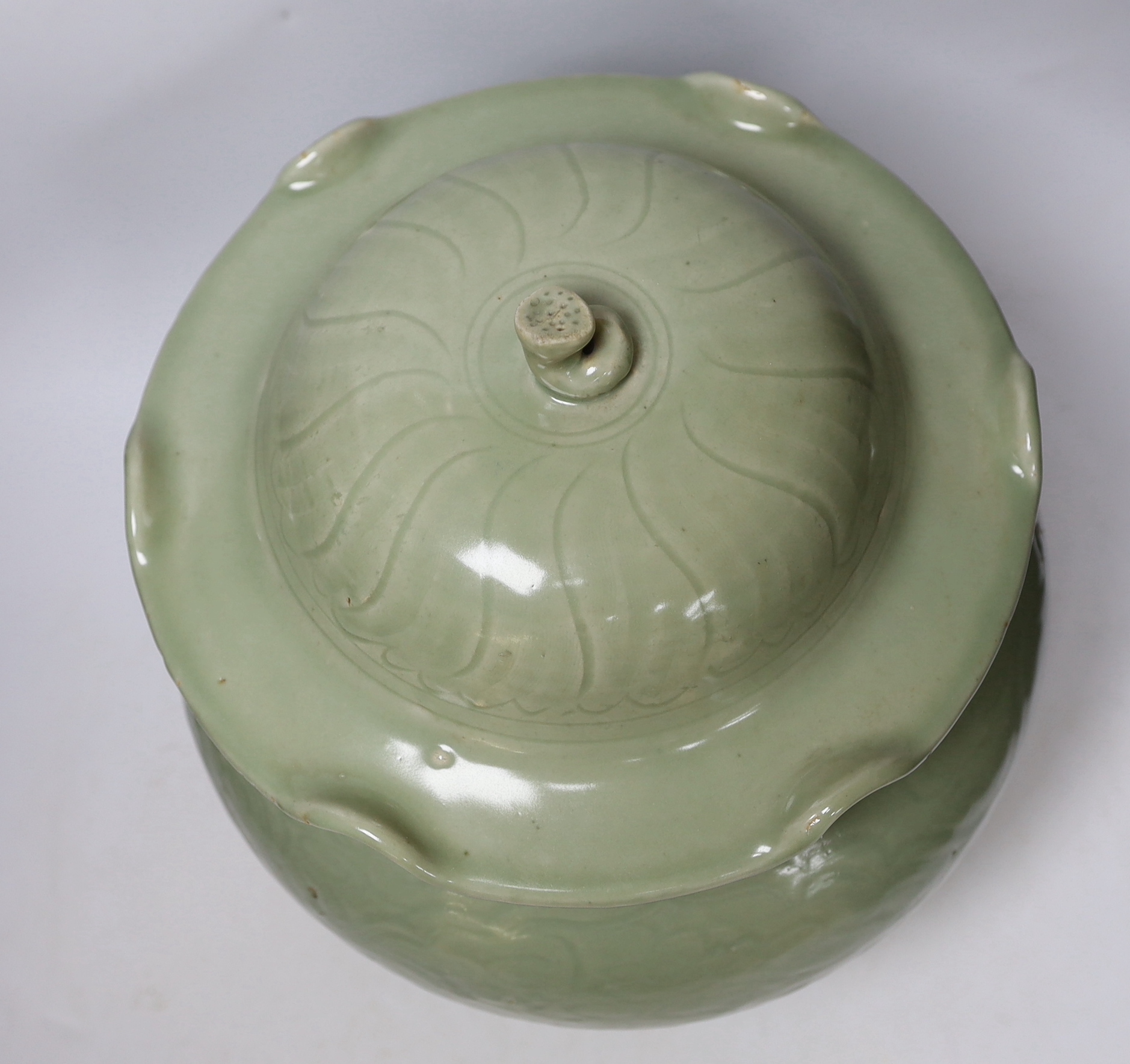 A large Chinese celadon jar and cover, Ming dynasty or later, the lotus leaf shaped cover above a foliate carved baluster body, 35cm high